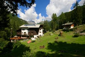 a house on a grassy hill next to a building at Albergo Villa Anna Maria in Champoluc
