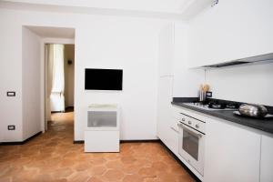eine Küche mit weißen Geräten und einem TV an der Wand in der Unterkunft Domus Festina Lente in Orvieto