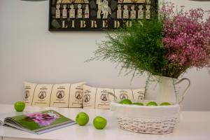 una mesa con un libro y un jarrón de flores y manzanas en Libredón Rooms, en Santiago de Compostela