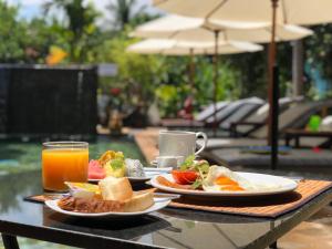 una mesa con dos platos de comida y un vaso de zumo de naranja en Nary Villa, en Siem Reap