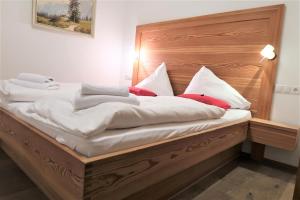 a bed with white sheets and red pillows on it at Mountain-Apart Simonhof in Maria Alm am Steinernen Meer
