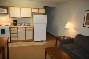 a kitchen with a refrigerator and a table and a couch at Affordable Suites Salisbury in Salisbury