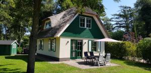 une maison verte et blanche avec une table et des chaises dans l'établissement Salland Vakantie, à Heeten