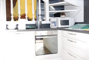 eine Küche mit weißen Schränken und einer Mikrowelle in der Unterkunft Studio le Sterne in Perros-Guirec