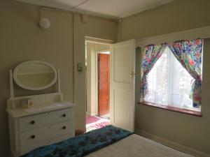 uma casa de banho com um espelho, uma cómoda e uma janela em Wiltshire Cottage em Port Alfred