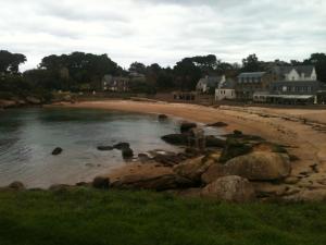 a beach with rocks in the water and houses at Studio le Sterne in Perros-Guirec