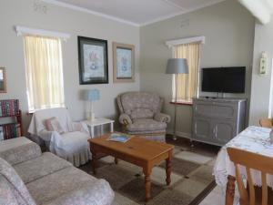 a living room with a couch and chairs and a tv at Wiltshire Cottage in Port Alfred