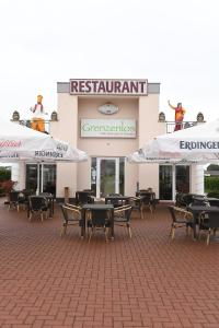 a restaurant with tables and umbrellas in front of a building at Pension Grenzenlos in Selfkant