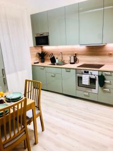 una cocina con armarios verdes, mesa y sillas en James Bond Apartment old town en Bratislava