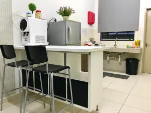 a kitchen with a counter with stools and a microwave at D'Q Putra Homestay Melaka Unit MIQA in Melaka