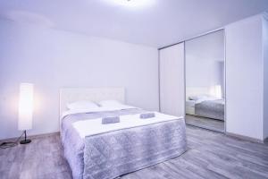 a white bedroom with a bed and a mirror at Отличная студия в центре Красноярска, район ЖД вокзала in Krasnoyarsk