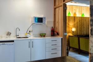 uma cozinha com armários brancos e uma televisão na parede em Casa Do Populo em Ponta Delgada