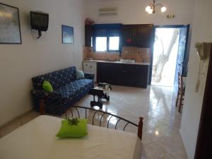 Livadi Astypalaias的住宿－梅勒尼奧公寓酒店，一间带桌子和沙发的客厅以及一间厨房。