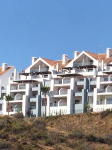 a white apartment building on a hill with palm trees at LA CALA HILL CLUB (LOS CORTIJOS) in La Cala de Mijas