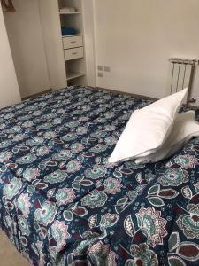 a bed with a pillow and a blue and white bedspread at Dto nuevo barrio Universitario con wifi y cochera-Check in express in Bahía Blanca