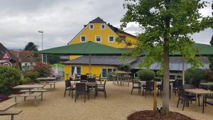 un edificio amarillo con mesas, sillas y una sombrilla verde en KM Hotel Murtal, en Knittelfeld