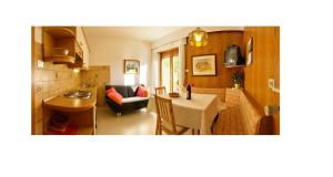 a kitchen and living room with a table and a couch at Appartments Geislerblick in Castelrotto