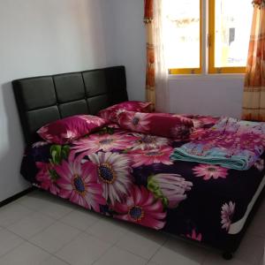 1 cama con colcha floral y almohadas en Homestay Andari, en Batu