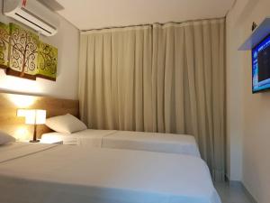 a hotel room with two beds and a television at MAKAIBA FLATS De Luxo in Porto De Galinhas