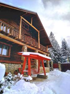 a log cabin in the snow with a red umbrella at Seventh Heaven in Mykulychyn