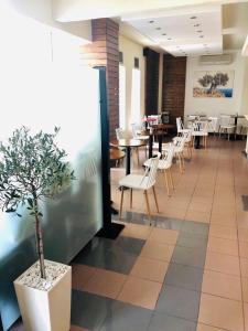 a restaurant with tables and chairs and a potted tree in a room at SimOtel Ermis in Hanioti