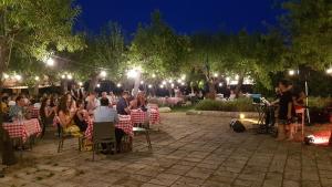 een menigte mensen die 's nachts aan tafel in een tuin zitten bij Hotel La Corte Del Sole in Noto