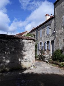 an old stone building with a wall and a street at Galerie Benjamine in Vézelay
