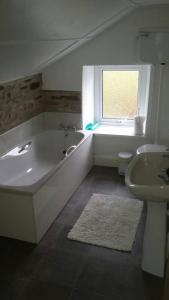Baño blanco con bañera y lavamanos en Ffyllon Fawr, en Henfynyw Upper