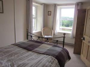 a bedroom with a bed and a chair and a window at Ffyllon Fawr in Henfynyw Upper