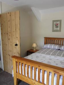 1 dormitorio con cama de madera y puerta de madera en Ffyllon Fawr, en Henfynyw Upper