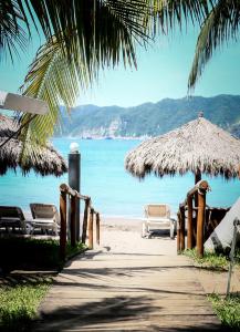 un camino a la playa con sillas y sombrilla de paja en La Quinta Gran Bahía, Cuastecomates - Todo Incluido, en Cuastecomate