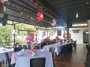 a dining room with white tables and pink balloons at Hotel El Ganadero in El Total