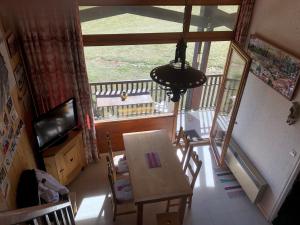Zimmer mit einem Tisch, einem TV und einem Balkon in der Unterkunft Appartement Au Pied Des Pistes in Puy-Saint-Vincent