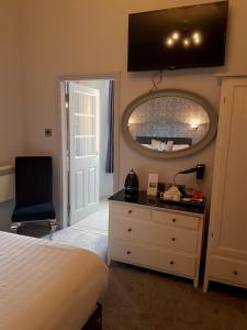 a bedroom with a bed and a mirror and a dresser at Mount Stewart Hotel in Portpatrick