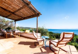 eine Terrasse mit Stühlen, einem Tisch und Meerblick in der Unterkunft su mari su entu Isola di Sant'Antioco villa con accesso diretto al mare in SantʼAntioco Ponti