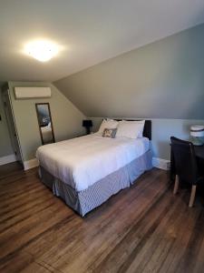 a bedroom with a large bed and a desk and a bed sidx sidx at By The River B&B in Fredericton