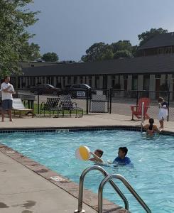 twee kinderen spelen in een zwembad met een bal bij Vintage Block Inn & Suites in Okoboji
