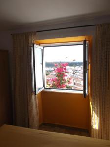 a window in a bedroom with a view of a flowering tree at Encosta do Castelo in Portel