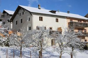 un edificio con árboles nevados delante de él en Il Maschun im historischen Engadinerhaus, en Scuol