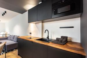 uma cozinha com armários pretos, um lavatório e um sofá em Dreamyflat - loft opera em Paris