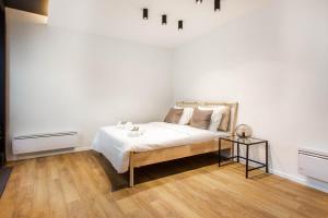 a white bedroom with a bed and a side table at Dreamyflat - loft opera in Paris