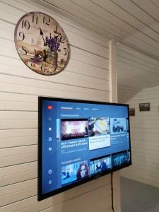 a clock hanging on a wall with a flat screen tv at GARDEN CHALET in Daugavpils