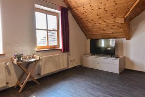 a room with a tv and a table and a window at Ferienwohnung Waldblick in Kleinsteinhausen