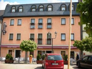 une camionnette rouge garée devant un bâtiment dans l'établissement Hotel Milin, à Reichenbach im Vogtland