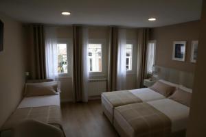 a bedroom with two beds and two windows at Aires do Umia in Caldas de Reis