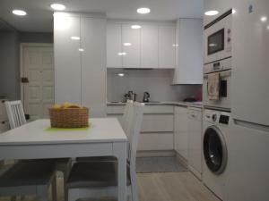 - une cuisine blanche avec une table et un lave-linge dans l'établissement Marisol apartament, à Saint-Jacques-de-Compostelle