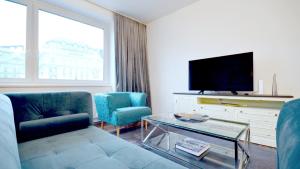 ein Wohnzimmer mit einem Sofa, 2 Stühlen und einem TV in der Unterkunft Vienna Residence, Naschmarkt - Karlsplatz in Wien