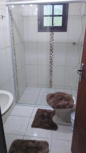 a bathroom with a shower and a toilet with rugs at Aconchego em Minas - Goncalves -Bairro Costas in Gonçalves +19 photos