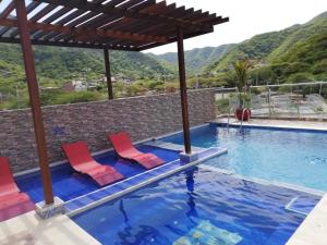 a swimming pool with two red chairs and a swimming pool at Hostal Casa Roma in Taganga