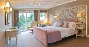 una grande camera da letto con un grande letto e una scrivania di Burn How Garden House Hotel a Bowness-on-Windermere